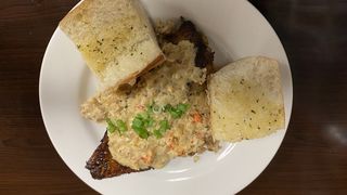 Black sea bream white wynn and rice sauce served on a plate with 2 slices of garlic bread